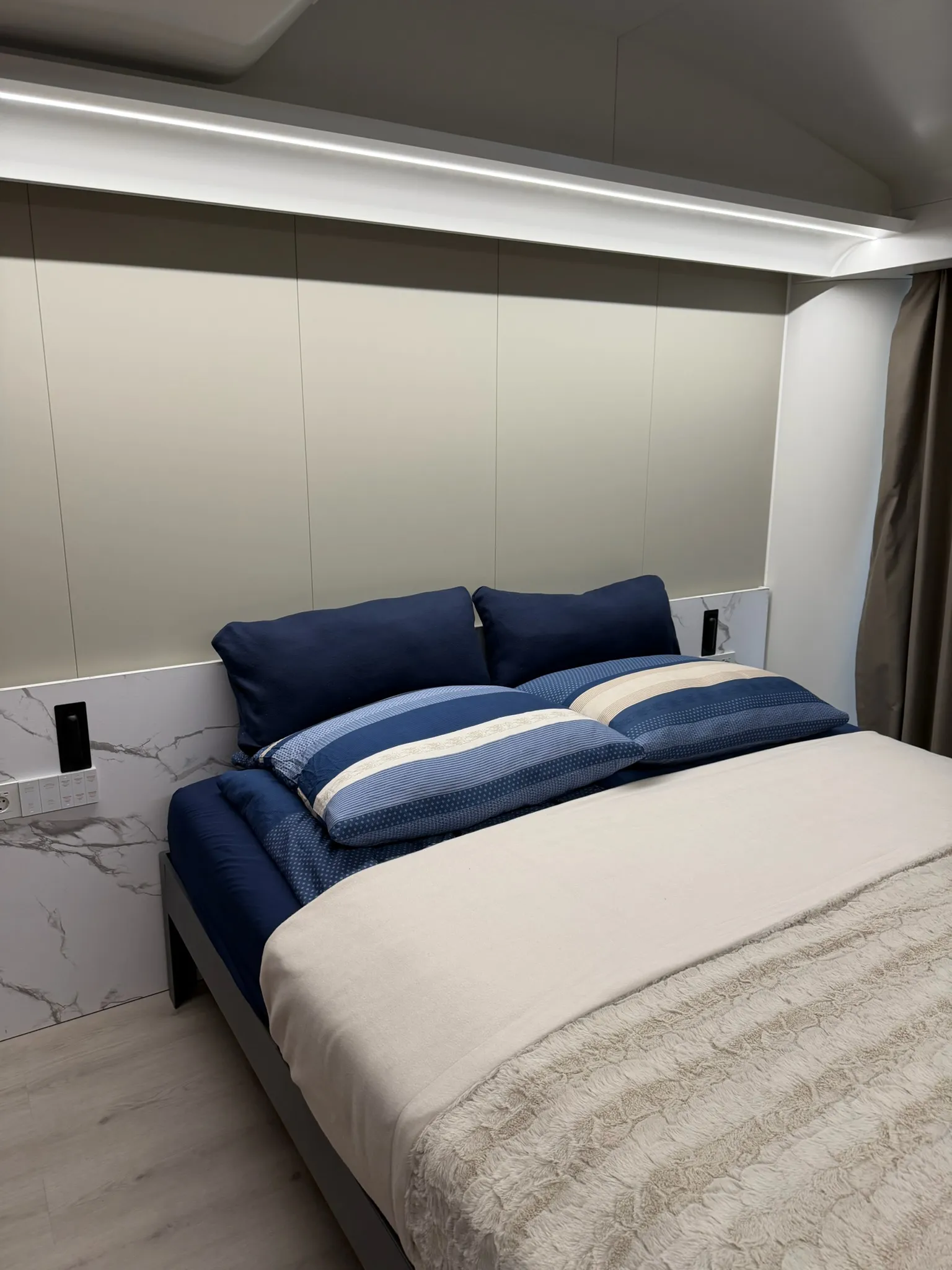 Schlafbereich der MK I am Abend mit Doppelbett und indirekter Beleuchtung über dem Kopfteil