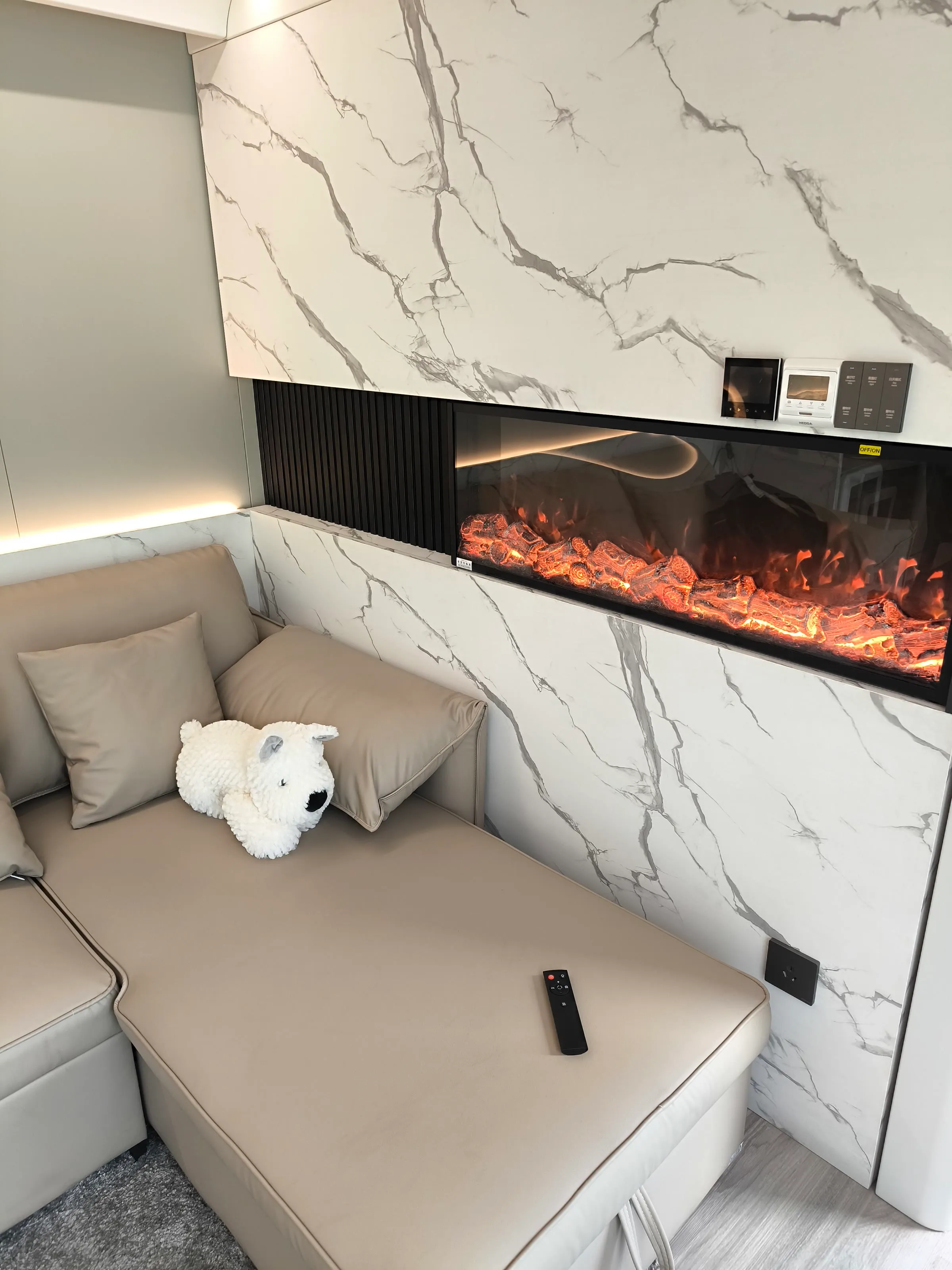 Loungebereich einer Wohnzelle mit Sofa und elektrischem Kamin