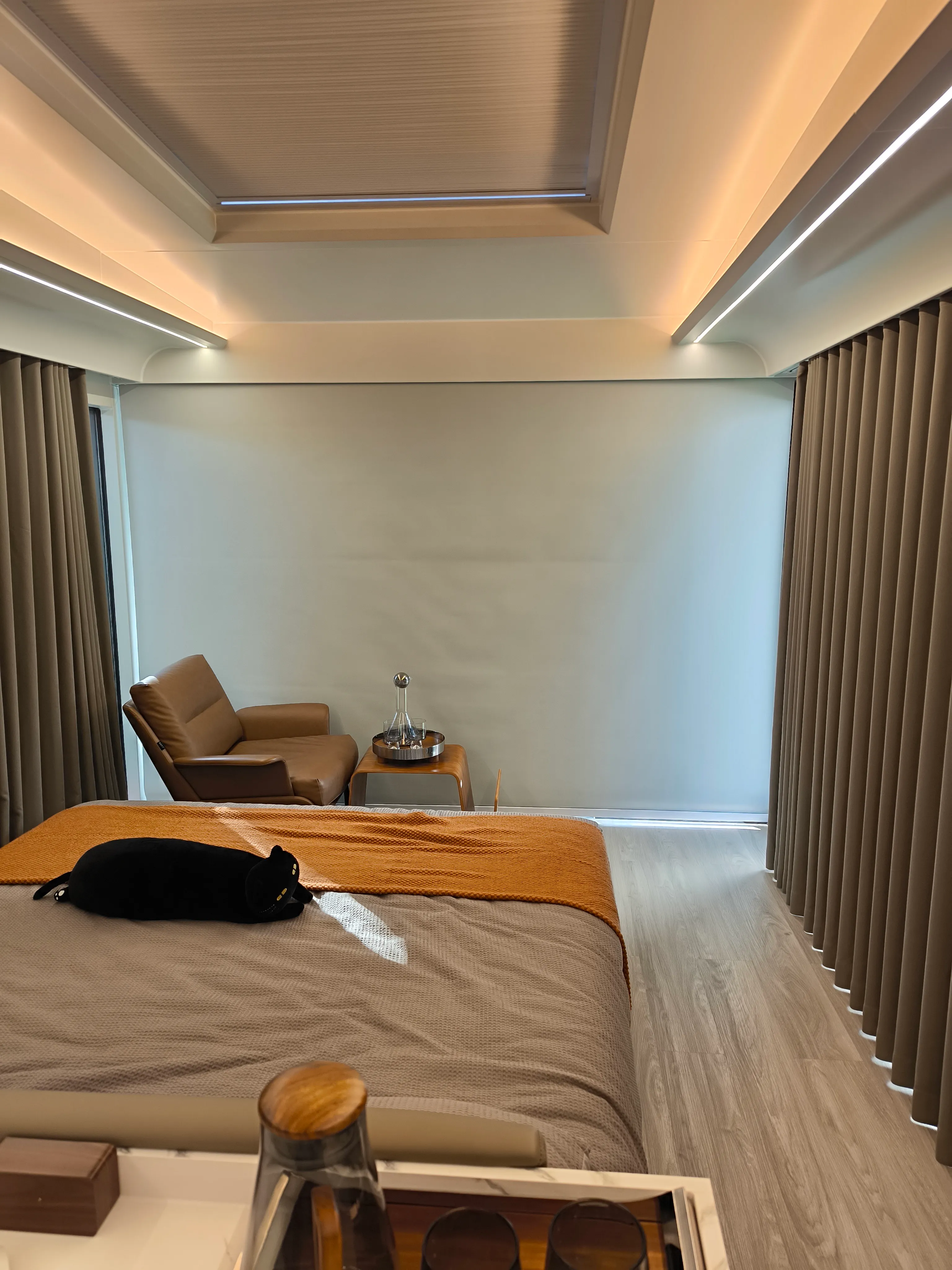Schlafbereich mit Doppelbett, Vorhängen, Sessel und umlaufender Lichtlinie