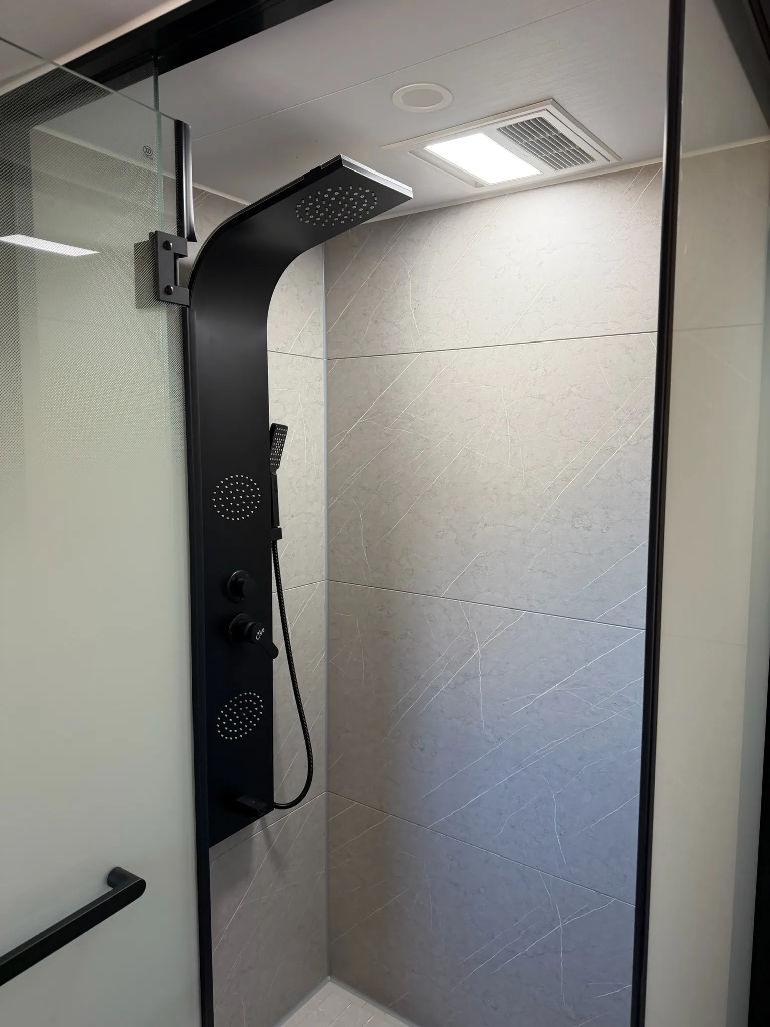 Dusche der MK I mit schwarzem Duschpaneel, Regenbrause und Glastür