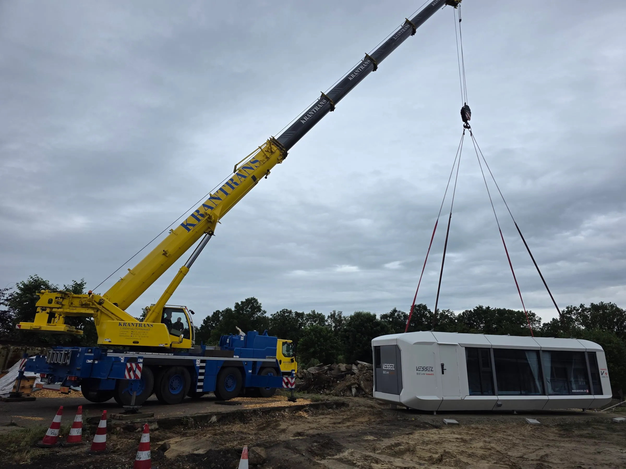 Mobilkran hebt die Wohnzelle MK I vom Auflieger auf den vorbereiteten Standplatz
